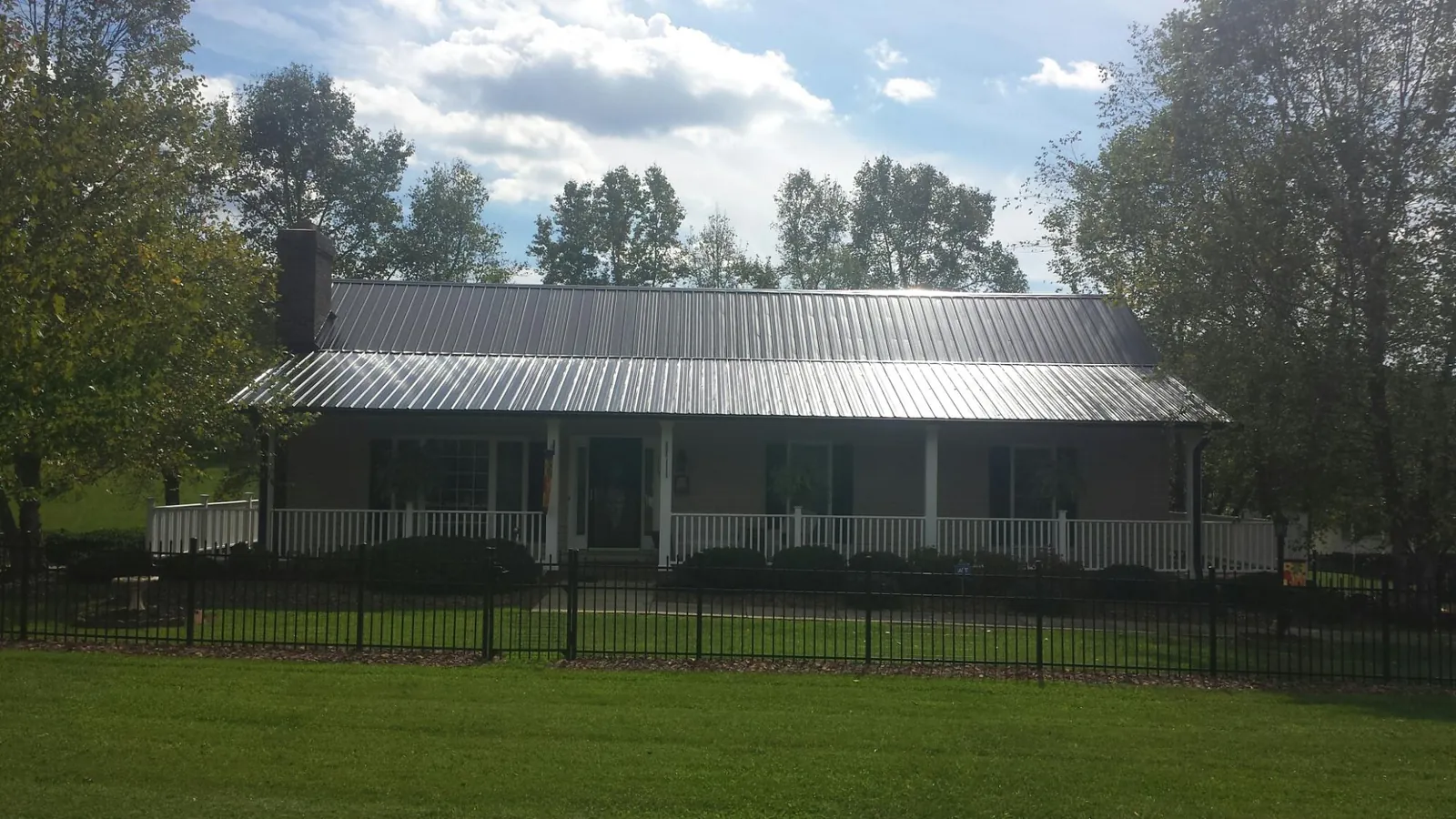 Gray metal roof on a brick ranch with a full width front porch — Gutter Guard Installation work by our crew in South New Berlin