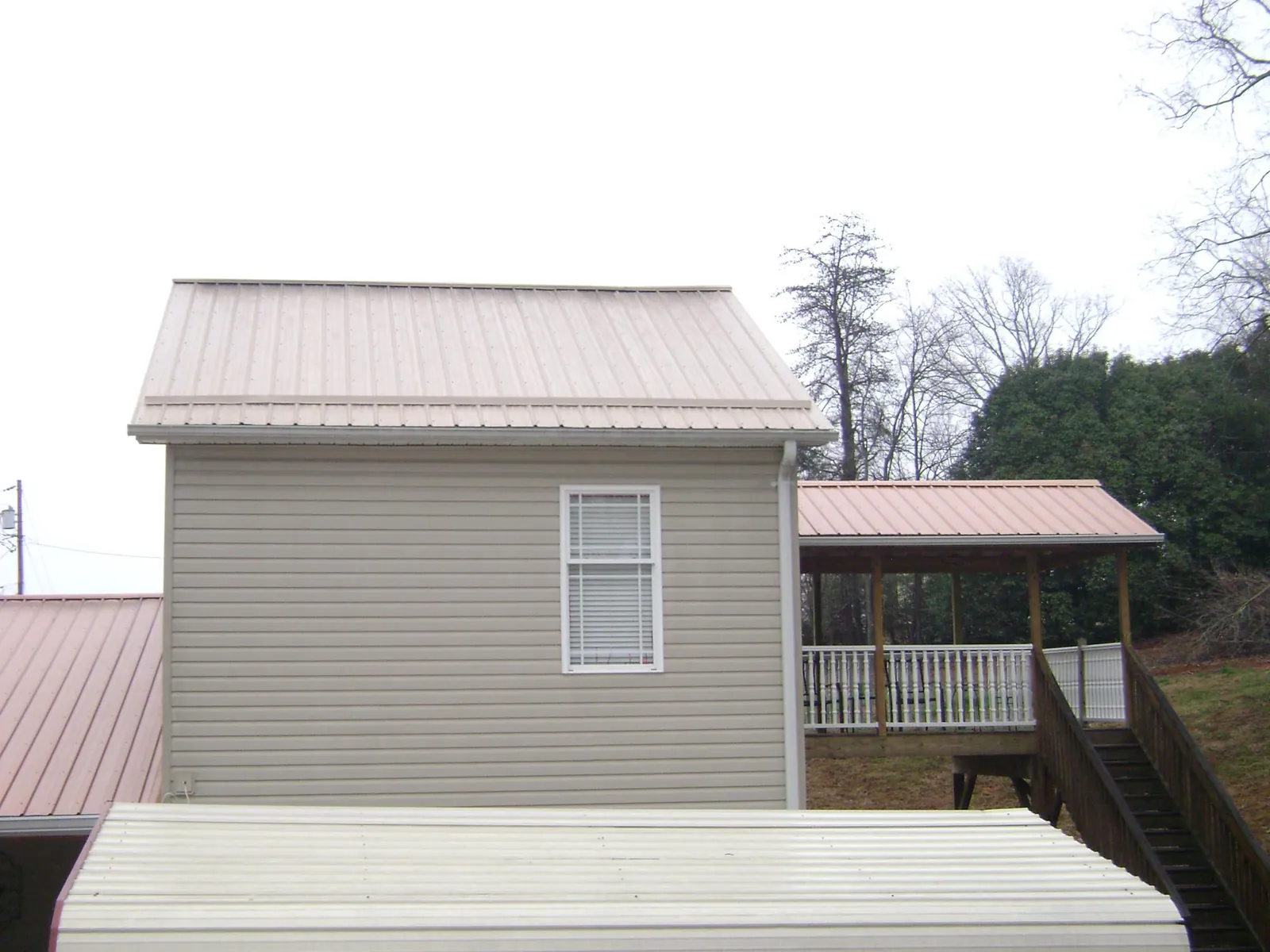 Tan metal roofs on a two story addition and attached porch, from a Roof Replacement job in South New Berlin