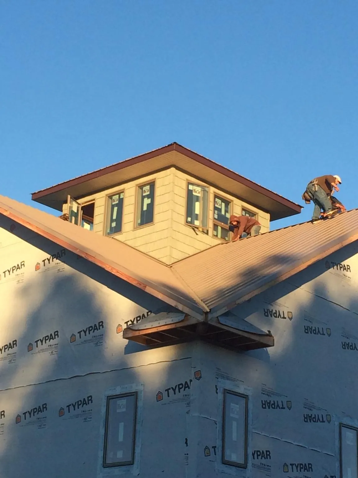 Roofers working around a rooftop cupola on a new metal roof at sunset — Roof Waterproofing in South New Berlin by Roofing Brothers
